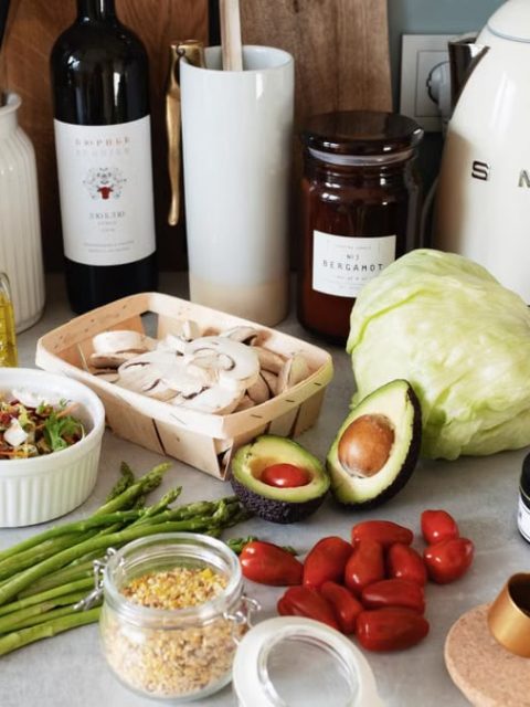 Assorted healthy food and vegetables set locating on gray countertop next to various utensils and appliances during cooking in stylish kitchen