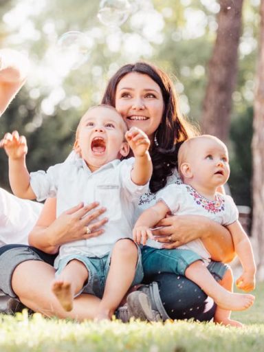 Joyful family enjoying a sunny day in the park while playing with bubbles.
