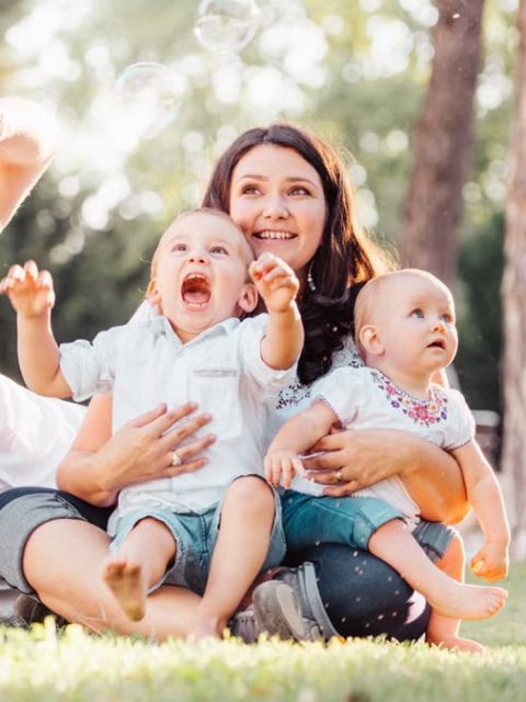Joyful family enjoying a sunny day in the park while playing with bubbles.