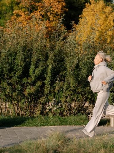 Elderly woman enjoying a healthy jog in a scenic park, showcasing active lifestyle.