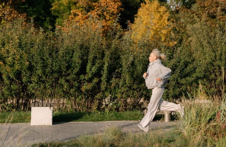 Elderly woman enjoying a healthy jog in a scenic park, showcasing active lifestyle.